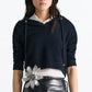 A woman wears the Dorothee Schumacher Modern Statements Pullover over a white collared shirt, paired with a black leather skirt featuring a bold silver flower accent at the waist.