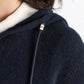 Close-up of a person wearing the Dorothee Schumacher Modern Statements Pullover, a cropped dark navy hoodie with a gold metal-tipped drawstring. Only part of their face, shoulder, and hair is shown.