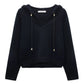 The Dorothee Schumacher Modern Statements Pullover is a black, long-sleeve cropped hoodie with a V-neck, metallic-tipped drawstrings, and a boxy fit for contemporary comfort.