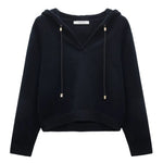 The Dorothee Schumacher Modern Statements Pullover is a black, long-sleeve cropped hoodie with a V-neck, metallic-tipped drawstrings, and a boxy fit for contemporary comfort.