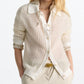 A woman wears the Dorothee Schumacher Airy Softness Cardigan—cream-colored, alpaca-wool blend with button front—over a collared shirt and beige pants, standing against a white background.