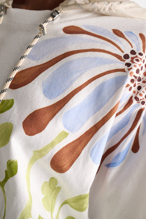 The Dorothee Schumacher Daydream Flower Shirt features a large floral print with blue and brown petals, green stems, dropped shoulders for comfort, and a black-and-white striped drawstring.