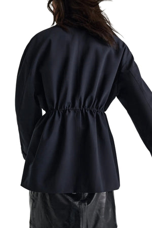 A person wearing the Dorothee Schumacher Casual Attraction Jacket, shown from the back against a white background, paired with a black leather skirt.