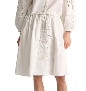 A person wearing Dorothee Schumacher’s Embroidered Beauty Skirt and a matching blouse with crochet-trimmed, embroidered sleeves.