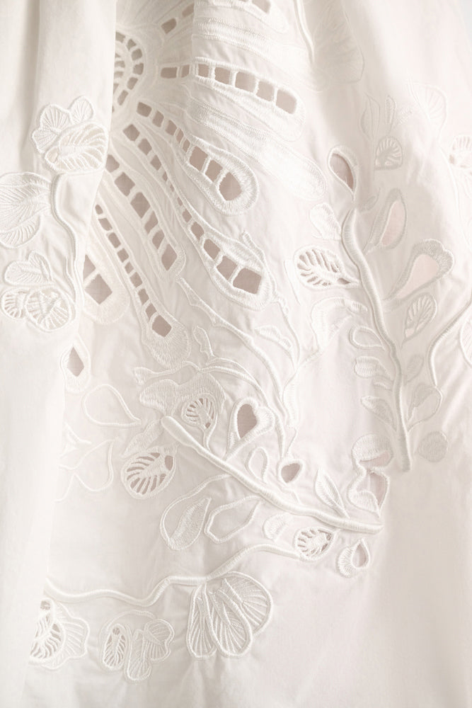 Close-up of the Dorothee Schumacher Embroidered Beauty Skirt, a white cotton piece with intricate floral embroidery and delicate cut-out details.