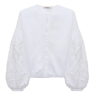 The Embroidered Beauty Blouse by Dorothee Schumacher is a white cotton top with a round neckline, long balloon sleeves, and detailed floral embroidery.