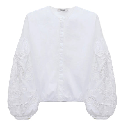 The Embroidered Beauty Blouse by Dorothee Schumacher is a white cotton top with a round neckline, long balloon sleeves, and detailed floral embroidery.