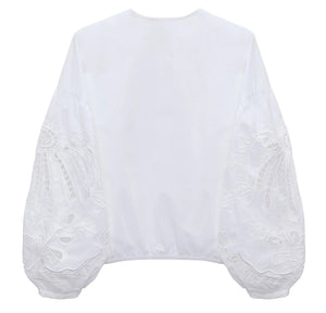 The Embroidered Beauty Blouse by Dorothee Schumacher is a white cotton top with long balloon sleeves, detailed with floral embroidery and geometric patterns, shown from the back against a plain backdrop.