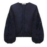 The Embroidered Beauty Blouse by Dorothee Schumacher features a navy blue cotton design with a round neck, voluminous long sleeves, intricate floral embroidery, and elegant cut-out details.