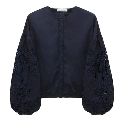 The Embroidered Beauty Blouse by Dorothee Schumacher features a navy blue cotton design with a round neck, voluminous long sleeves, intricate floral embroidery, and elegant cut-out details.