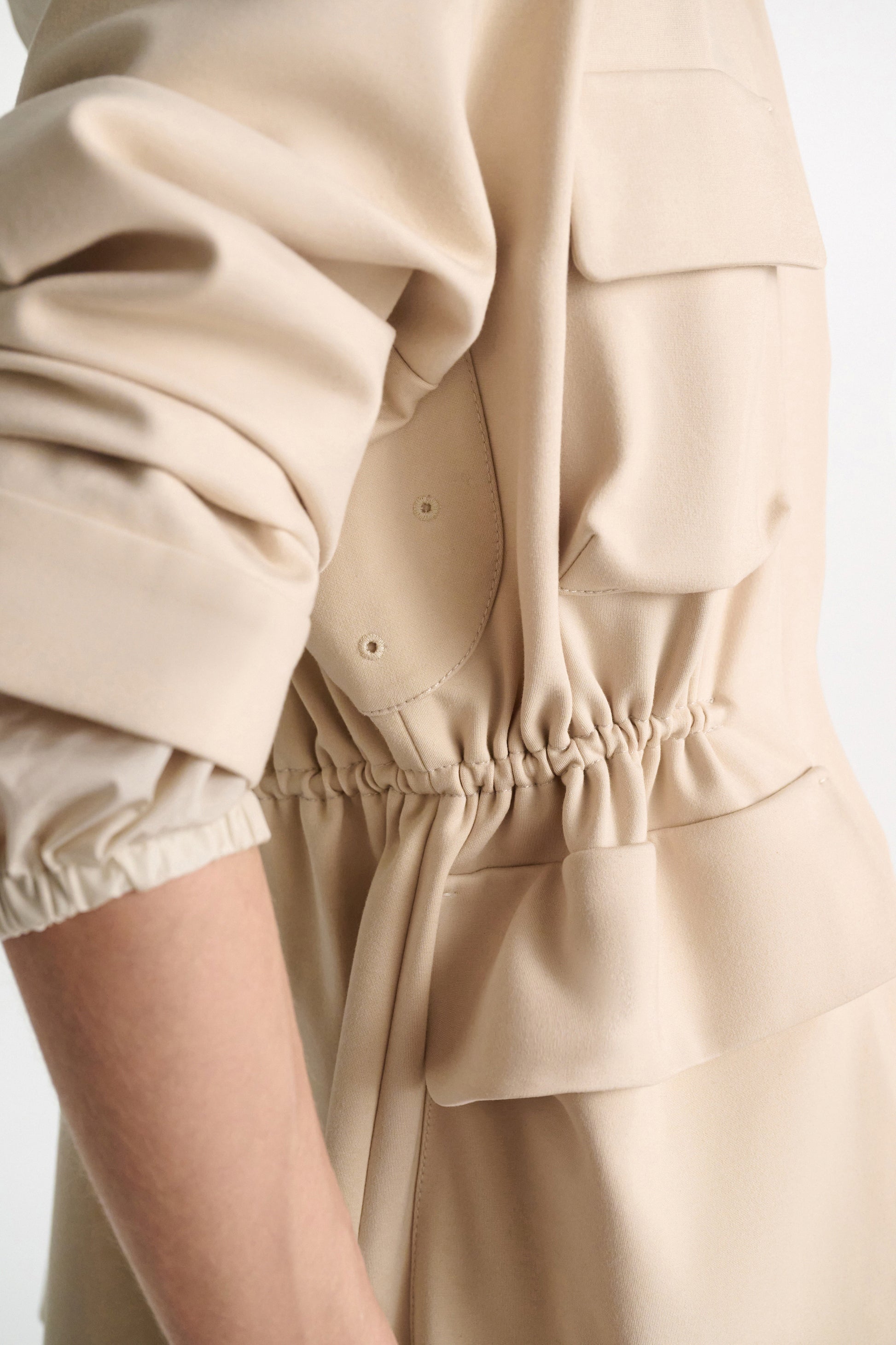 Close-up of the Dorothee Schumacher Emotional Essence Jacket in beige, featuring long sleeves, an adjustable drawstring waist with gathered detail, and visible pocket flaps.