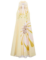 The Floral Power Dress by Dorothee Schumacher is a sleeveless pale yellow cotton poplin midi-dress with a halter neckline and a large signature floral print in pink, white, and yellow on the front.