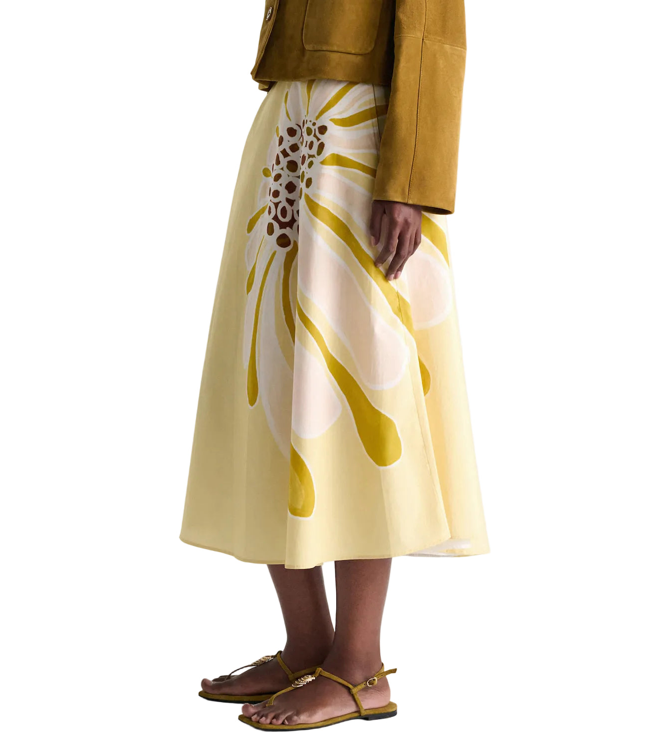 A person wears the Dorothee Schumacher Floral Power Skirt—a yellow signature print cotton poplin midi-skirt with a fitted waist—paired with a brown jacket and flat sandals, standing against a plain background.