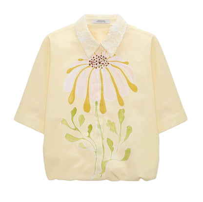 The Floral Power Blouse by Dorothee Schumacher is a light yellow cotton poplin top featuring a removable lace collar and a bold pastel pink, yellow, and green floral design on the front.