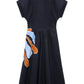 The Floral Power Dress by Dorothee Schumacher is a navy blue short-sleeved cotton poplin dress with a flared skirt and an abstract orange, white, and blue signature print near the hem on one side.