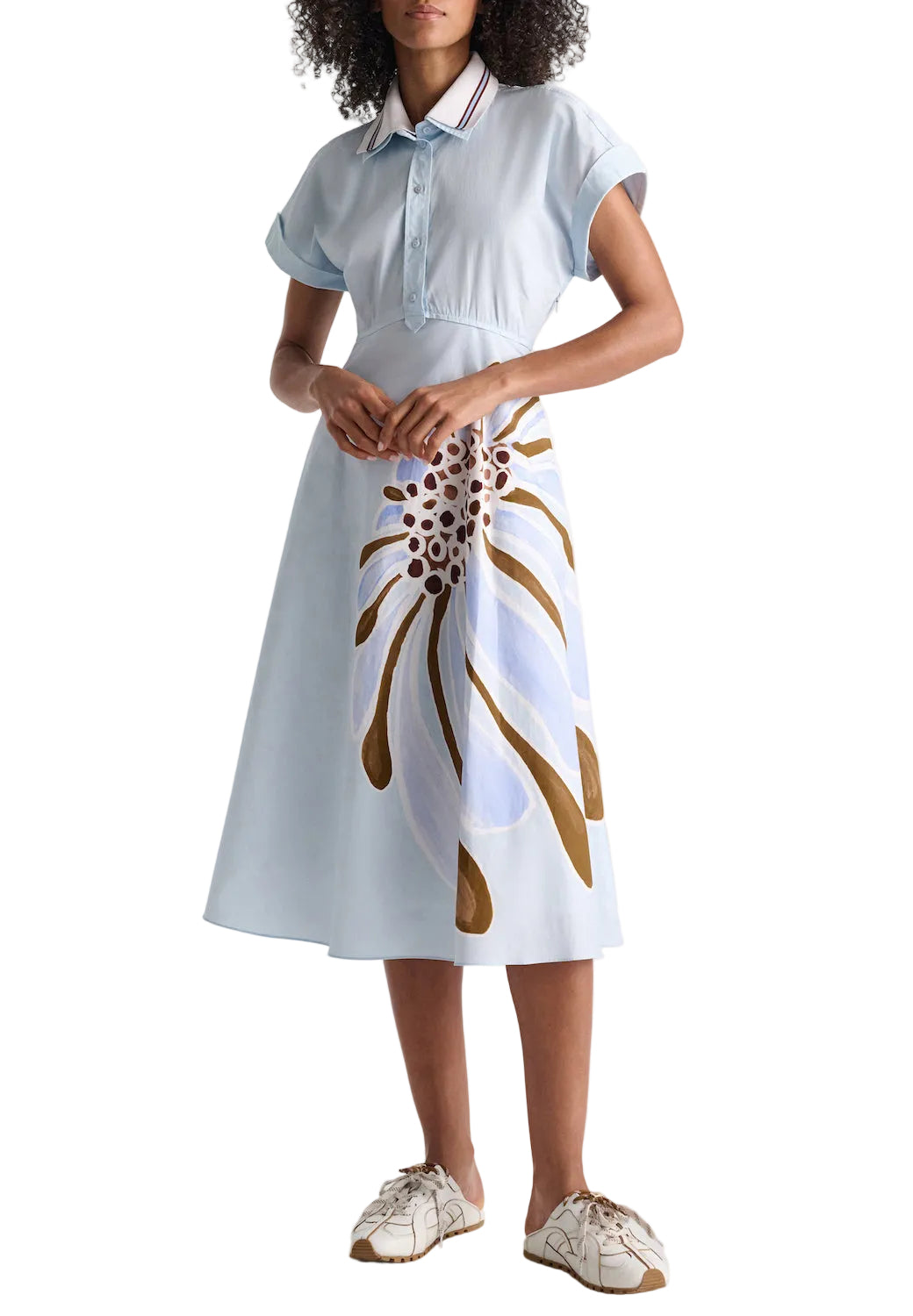 A person wearing the Dorothee Schumacher Floral Power Dress—light blue cotton poplin with a bold floral print on the skirt—and white sneakers, standing against a plain background.