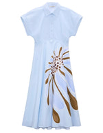 The Floral Power Dress by Dorothee Schumacher features light blue cotton poplin, a polo collar, short sleeves, button front, and a bold abstract brown and white floral print on the skirt.