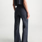 A woman is seen from behind wearing Dorothee Schumacher's Fluid Denim Pants—high-waisted, wide-leg, dark denim with subtle braid detailing—paired with a sleeveless matching top against a plain light background.