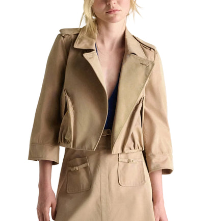 A woman wears Dorothee Schumacher's Luxury Layer Jacket, a cropped cotton piece with 3/4 sleeves and large lapels, paired with a matching high-waisted skirt with front pockets.