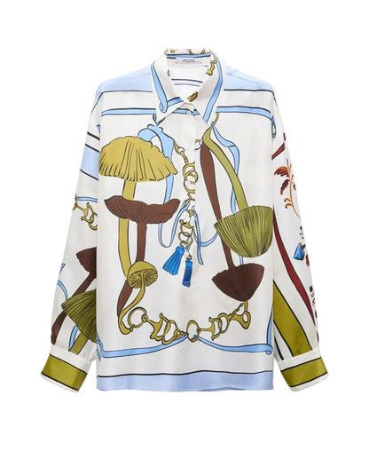 Dorothee Schumacher’s Cosmic Funghi Blouse is a long-sleeve button-up crafted in silk twill, showcasing a vibrant oversized mushroom and chain print in shades of blue, olive, and brown on a white background.