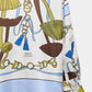 Introducing the Cosmic Funghi Blouse by Dorothee Schumacher—an oversized silk twill blouse adorned with blue, green, and brown abstract shapes, gold chain motifs, and tassel details. The fabric features "Dorothee Schumacher" text subtly printed throughout, making a statement with its elegant drape and distinctive design.