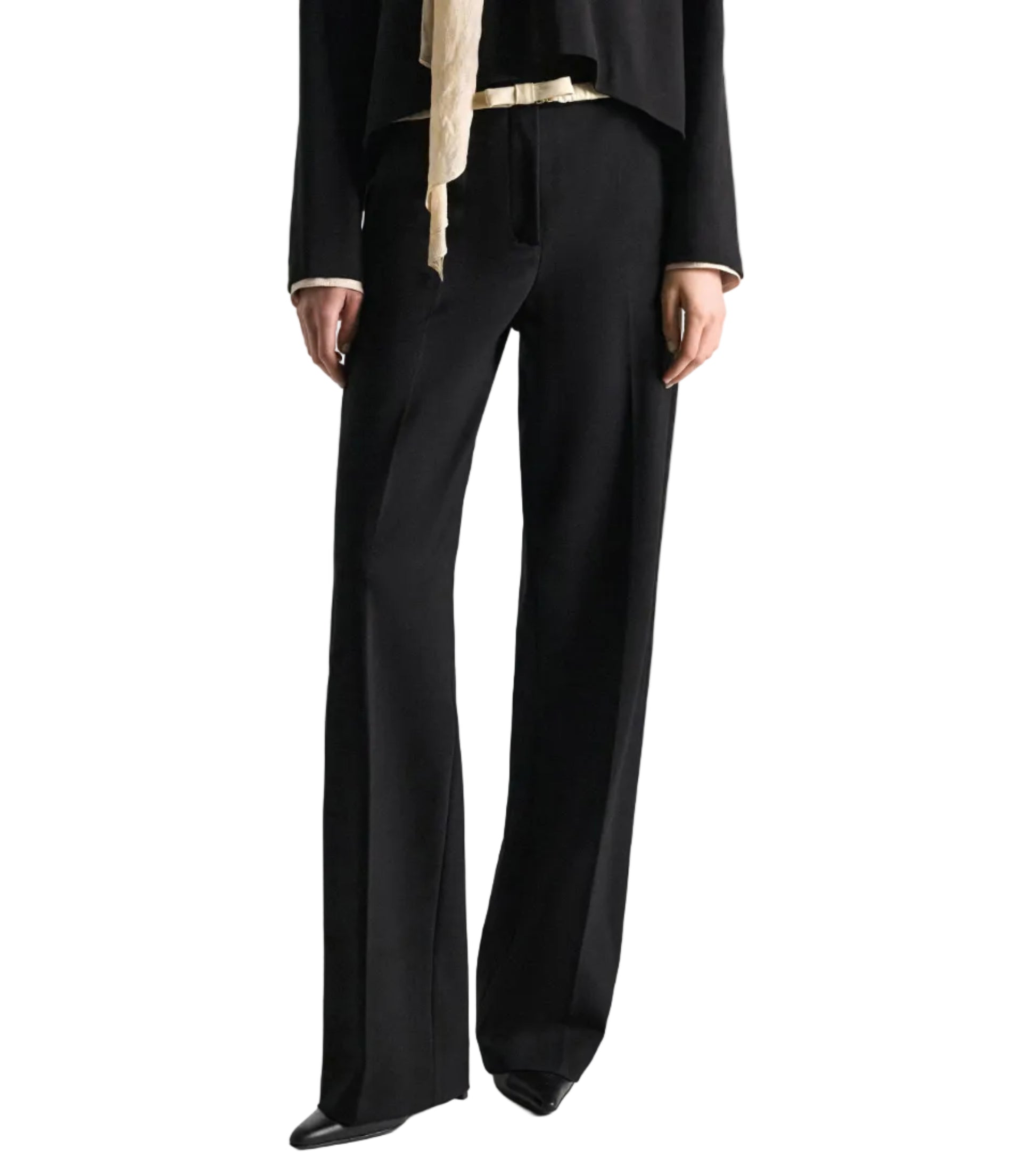 A person is seen wearing the Dorothee Schumacher Emotional Essence Pants—black wide-leg trousers with an unfinished hemline—styled with a black long-sleeve top and black shoes, standing with arms relaxed at their sides. The image is cropped below the shoulders against a white background.