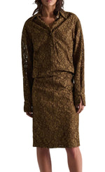 A person wearing the DS Powerful Lace Dress by Dorothee Schumacher—a brown guipure lace shirtdress featuring an elastic waist and a matching knee-length skirt—shown from the knees up.