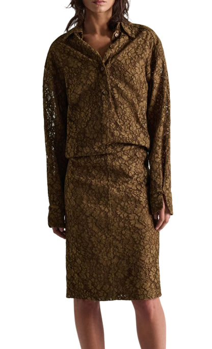 A person wearing the DS Powerful Lace Dress by Dorothee Schumacher—a brown guipure lace shirtdress featuring an elastic waist and a matching knee-length skirt—shown from the knees up.