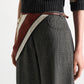 A person is wearing a dark sweater, high-waisted plaid trousers, and a signature print scarf—secured at the waist with the Dorothee Schumacher Cuoio Softness Scarf Belt. The image is cropped from the shoulders to mid-thigh.