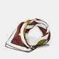 Introducing the Cuoio Softness Scarf Belt by Dorothee Schumacher, a luxurious silk accessory showcasing a geometric pattern in white, brown, yellow, and black, artfully folded and presented on a simple white backdrop.