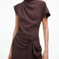 A person wearing the Staud Davina Dress—a short-sleeved, high-neck brown style with draped fabric, a knotted waist detail, and an elegant handkerchief hem—perfect for day-to-night wear.