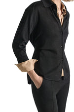 A black Shimmering Merino Cardigan with a subtle shimmer worn over a beige collared shirt.