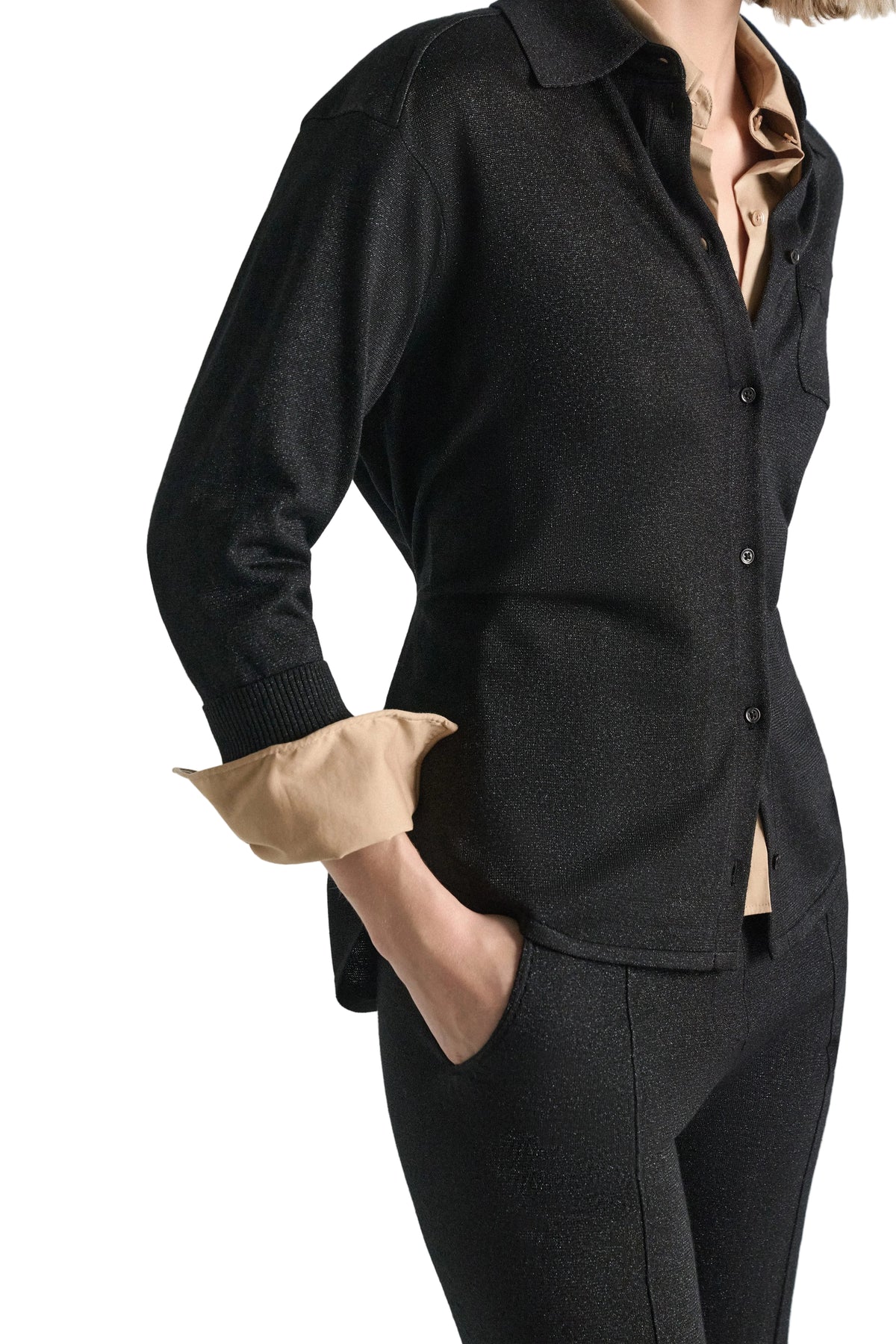 A black Shimmering Merino Cardigan with a subtle shimmer worn over a beige collared shirt.