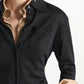 A black Dorothee Schumacher Shimmering Merino Cardigan with a chest pocket and self-tie sash, worn over a beige collared shirt with turned-up cuffs.