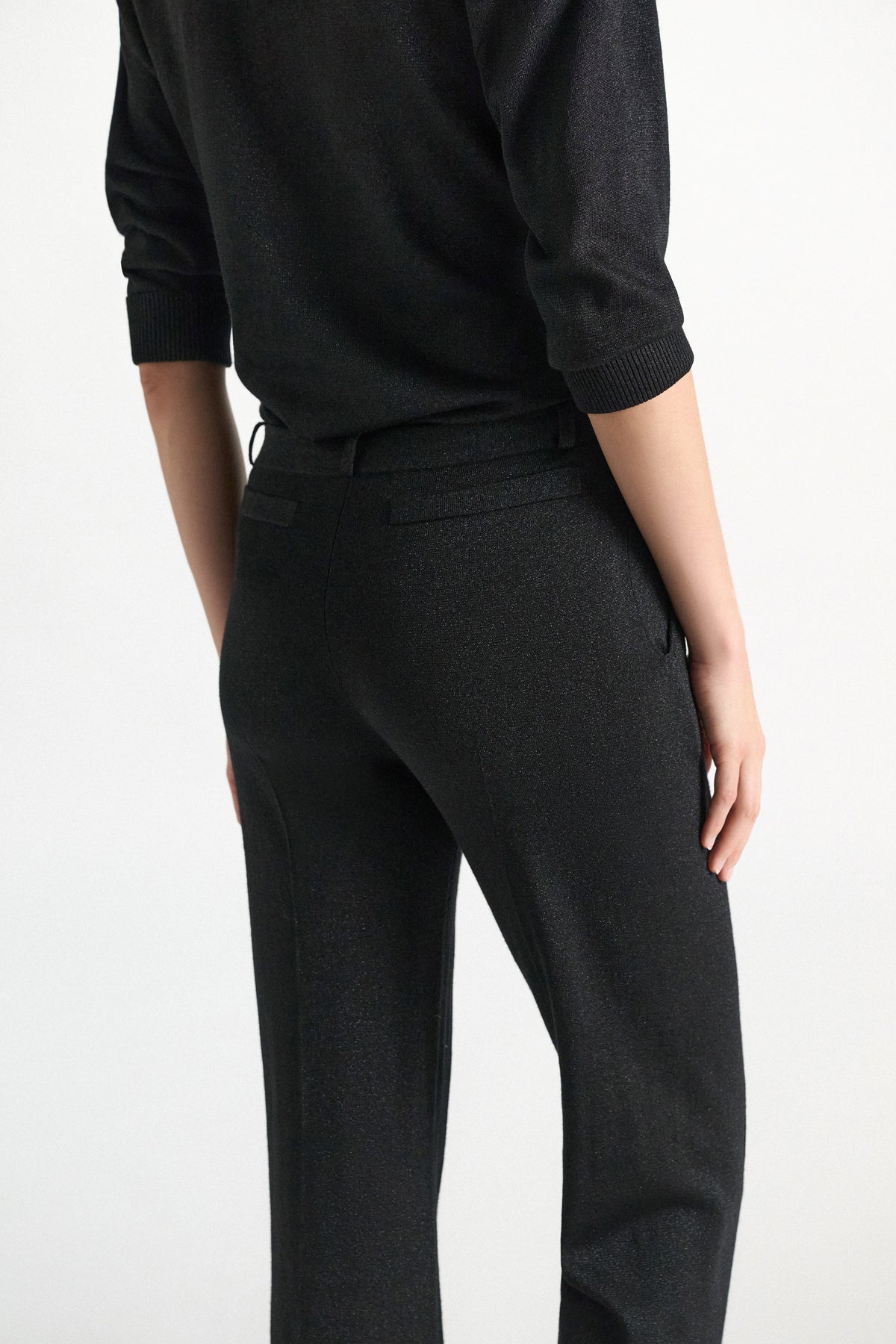 A person wearing a shimmering Merino-Lurex top and matching Shimmering Merino Trouser flared trousers.