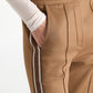 Close-up of tan quilted knit Everyday Cool Pant by Dorothee Schumacher, featuring a white and brown stripe down the side and a hand in the pocket.