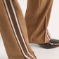 Dorothee Schumacher Everyday Cool Pant in tan quilted knit with side slits and brown and white racing stripes, worn with dark brown leather boots.
