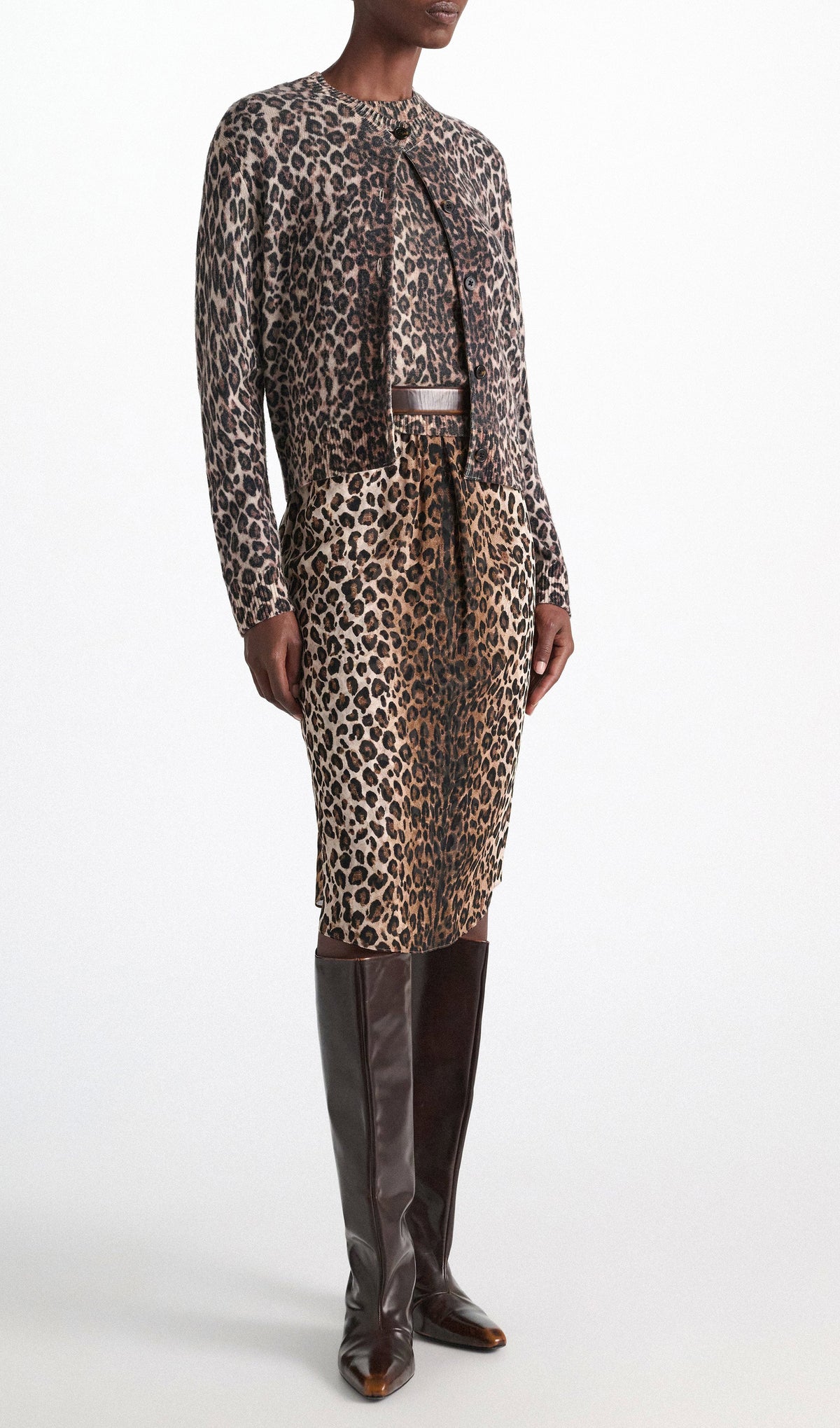 A person wearing a leopard print cardigan and the matching Dorothee Schumacher Wild at Heart Skirt with tall brown leather boots.