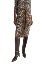 A person wears a leopard-print Wild at Heart Skirt and matching long-sleeved top paired with dark brown knee-high leather boots.