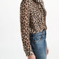 A woman wearing the Dorothee Schumacher Wild at Heart Blouse in leopard print viscose georgette with a high-collar tie-neck detail tucked into blue jeans.