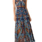 Woman wearing the Emporio Sirenuse Vivienne Brise Dress—a sleeveless navy maxi with a V-neck and colorful, intricate geometric and animal-inspired patterns—paired with flat sandals.