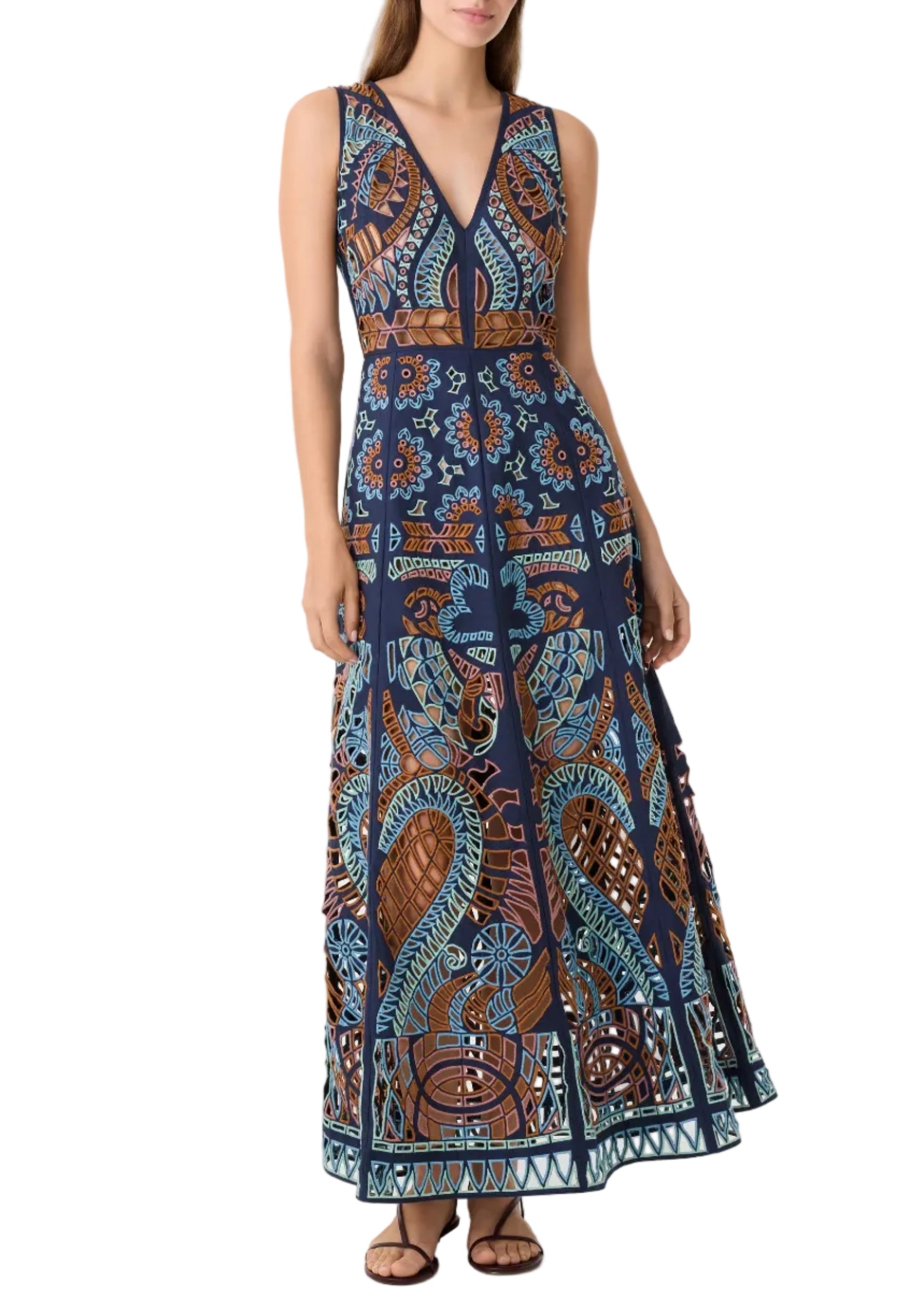 Woman wearing the Emporio Sirenuse Vivienne Brise Dress—a sleeveless navy maxi with a V-neck and colorful, intricate geometric and animal-inspired patterns—paired with flat sandals.