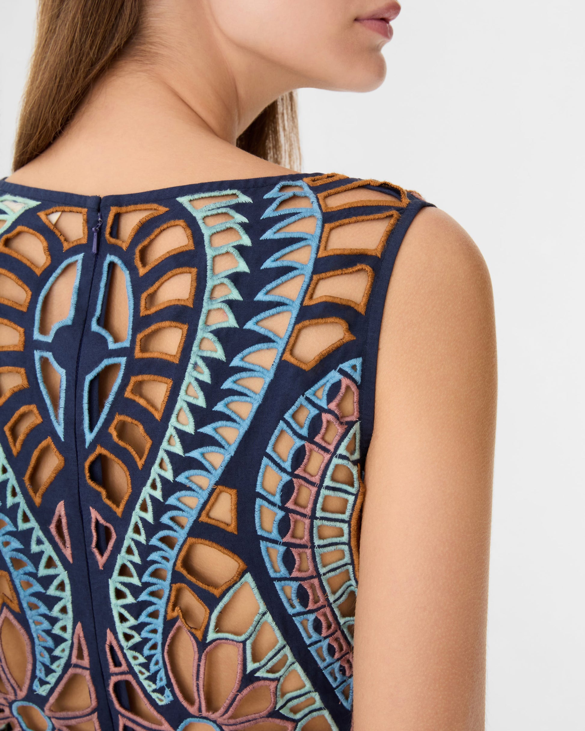 Close-up of a woman's upper back and shoulder wearing the sleeveless Vivienne Brise Dress by Emporio Sirenuse, detailed with colorful, intricate Brisé Cutwork and embroidered patterns.
