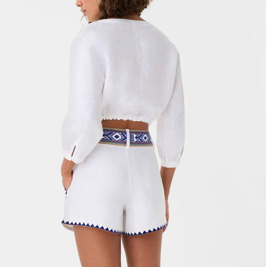 A person wearing the New Jinny Blue Horizon Top by Emporio Sirenuse and high-waisted shorts with blue geometric patterns, shown from the back against a plain background, inspired by Emporio Sirenuse’s chic style.