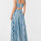 A woman, photographed from the back, wears the Emporio Sirenuse Flaminia Ikat Stripes Skirt—high-waisted, floor-length, in handwoven blue and white stripes—with a matching sleeveless crop top.
