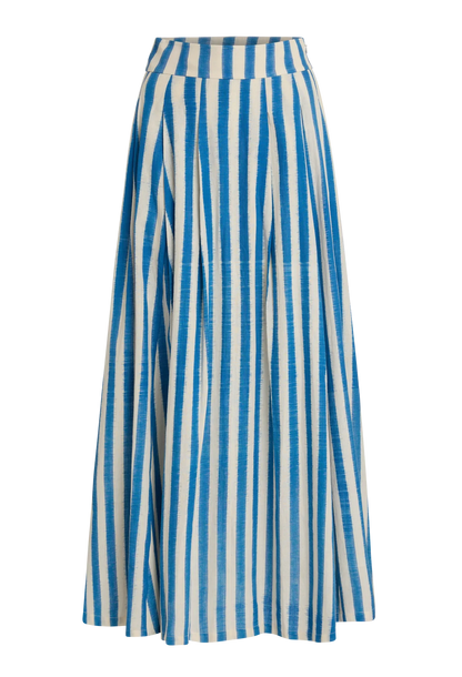 The Flaminia Ikat Stripes Skirt by Emporio Sirenuse is a long, high-waisted design with handwoven blue and white Ikat stripes, a wide waistband, and a flared, flowing silhouette.