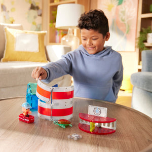 A smiling child in a blue hoodie embarks on a creative adventure, building and exploring with the Magnatiles Lighthouse 26-Piece Set on a round wooden table in the living room.