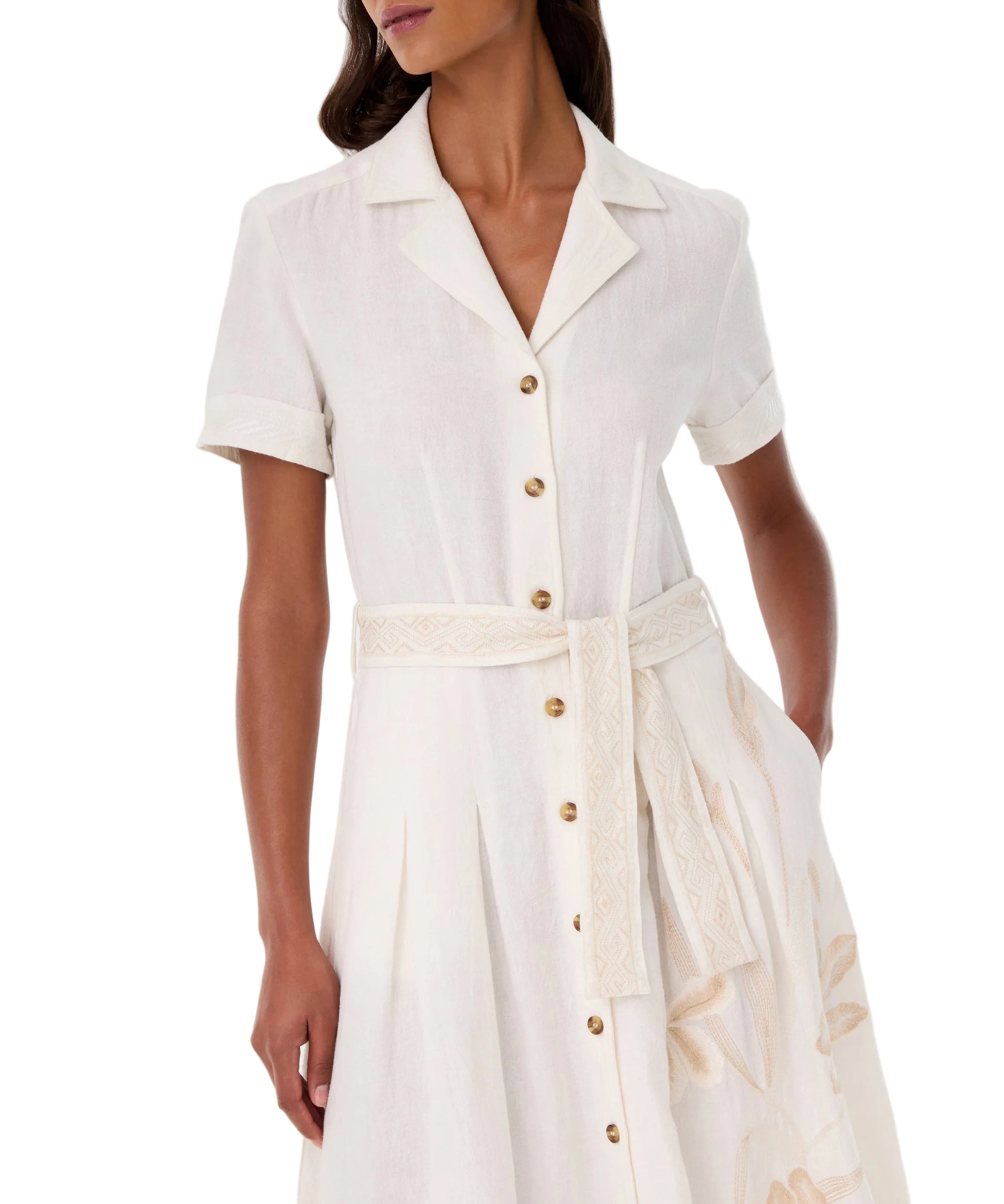 A woman wears the Emporio Sirenuse Daria Sand Flowers Dress—a collared, short-sleeve Japanese linen dress with a button front and matching fabric belt at the waist.