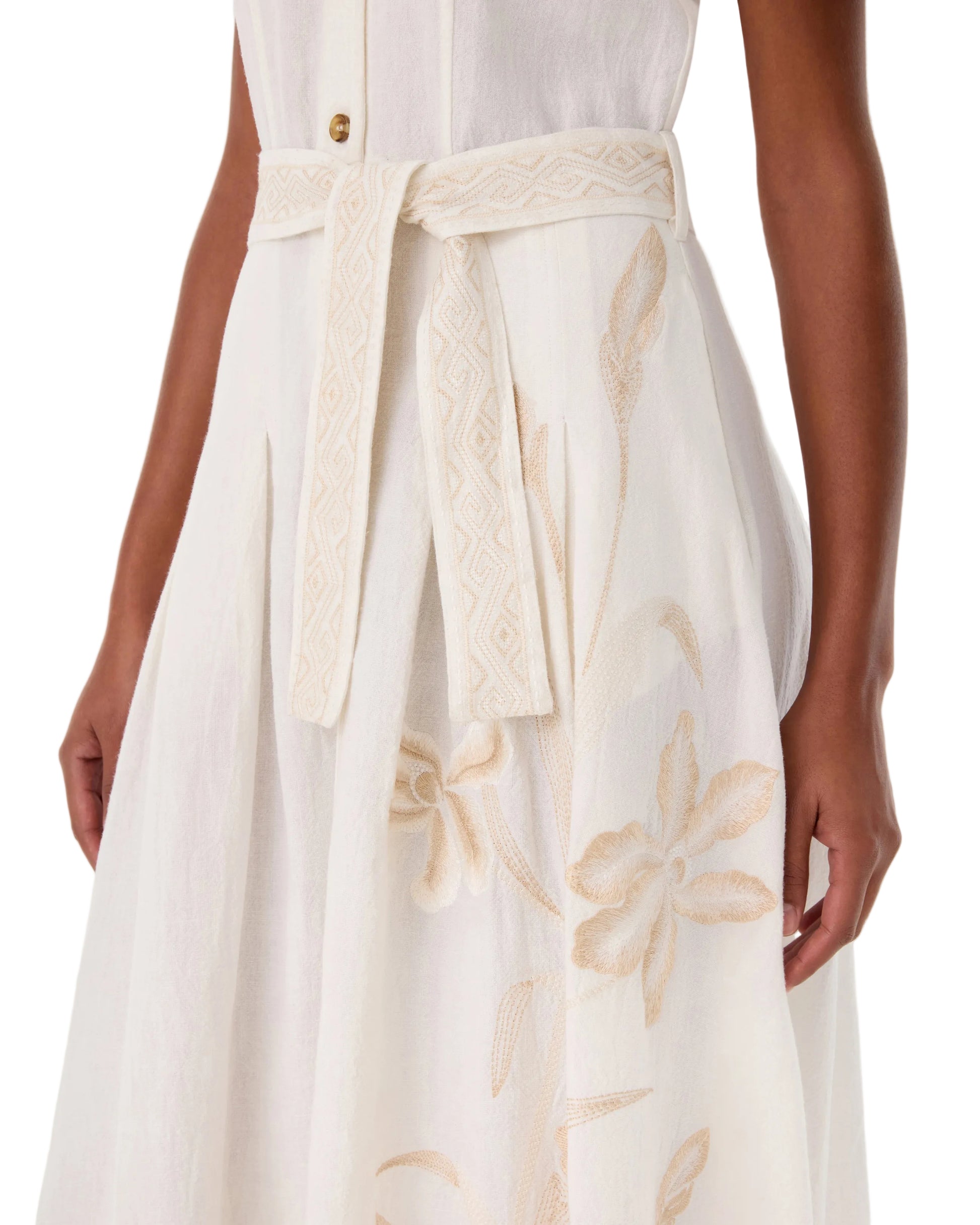 A woman wears the Emporio Sirenuse Daria Sand Flowers Dress, an ivory ramie piece featuring a fabric belt and beige Sand Flowers embroidery near the skirt.