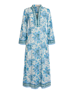 The Emporio Sirenuse Jenna Eastern Dream Dress is a long-sleeve, ankle-length cotton voile caftan with a blue print and decorative trim on the neckline, cuffs, and hem, shown against a white background.